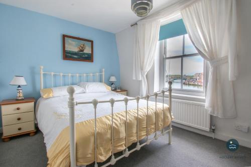 a bedroom with a bed and a large window at 14 Nothe Parade - Waterfront Holiday Cottage in Weymouth