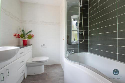 a bathroom with a tub and a toilet and a sink at 14 Nothe Parade - Waterfront Holiday Cottage in Weymouth