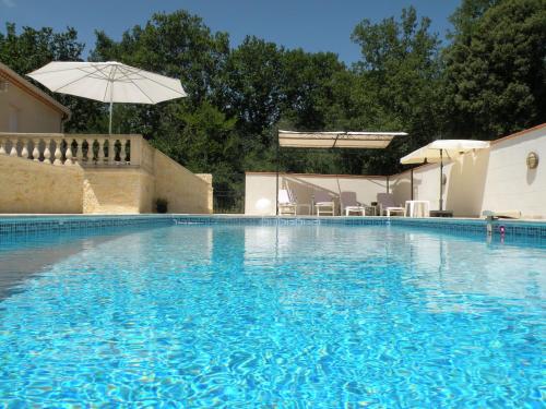 une grande piscine bleue avec un parasol dans l'établissement Mazet avec piscine à 6 kms d'Uzes, à Saint-Quentin-la-Poterie