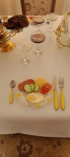 a table with a plate of vegetables and forks and knives at Cute Home in Bol'shevik