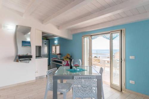 a dining room with a table and chairs and a kitchen at Vista Mare tra i luoghi di Montalbano in Punta Secca