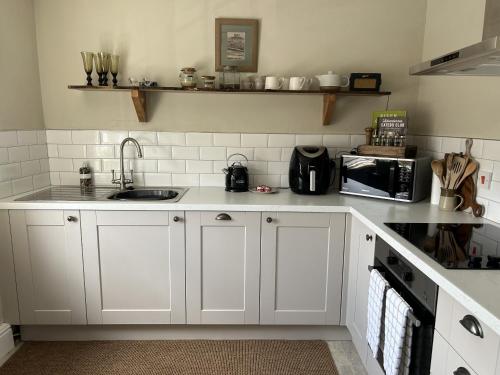 a white kitchen with a sink and a microwave at Bridport Town Centre Flat in Bridport