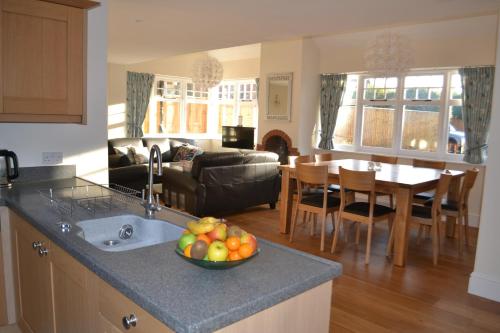 a kitchen and living room with a bowl of fruit on a counter at Bentley Cottage in Brockenhurst