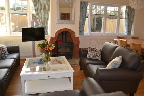 a living room with two leather couches and a fireplace at Bentley Cottage in Brockenhurst