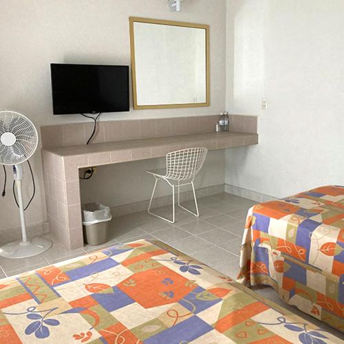 a bedroom with a bed and a desk with a television at Hotel Y Parque Acuático La Caldera in Abasolo