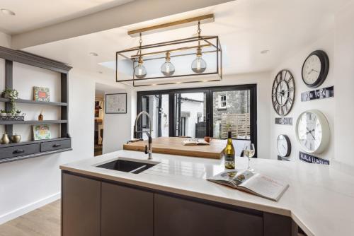 una cucina con lavandino e orologi appesi al muro di Coronation Family Cottage, Modernised 200-Year-Old Lake District Cottage with Private Hot Tub and Parking a Lindale