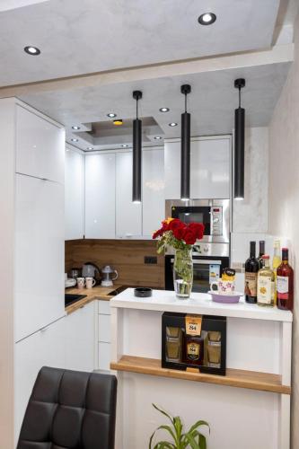 a kitchen with white cabinets and a counter with flowers at NelaLux in Podgradac