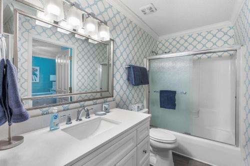 Un baño con lavabo, inodoro y espejo. en Grand Caribbean East, beach view, nearby beach access, en Destin