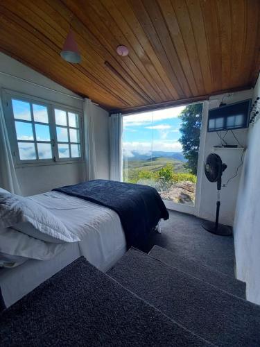 a bedroom with a bed and a large window at Chalés da Pedra in Lavras Novas