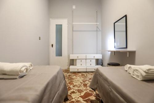 a white room with two beds and a mirror at Medea Suite Panoramic in Palermo