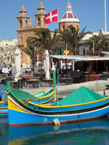 a group of boats sitting in the water near a building at Sea & Sky townhouses in Marsaxlokk