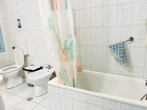 Un baño blanco con inodoro y bañera. en Kuti Hostel, en Lisboa