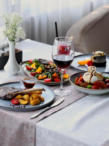 a table with two plates of food and a glass of wine at Praga Hotel in Tashkent