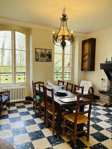 une salle à manger avec une table, des chaises et un lustre dans l'établissement Les Bons Amis, à Simard