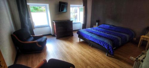 a bedroom with a bed and a chair and a window at Les hôtes de Labastide in Labastide-Rouairoux