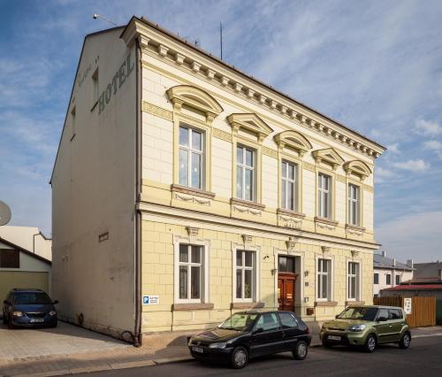 a large building with two cars parked in front of it at Pension Fontána Svitavy in Svitavy