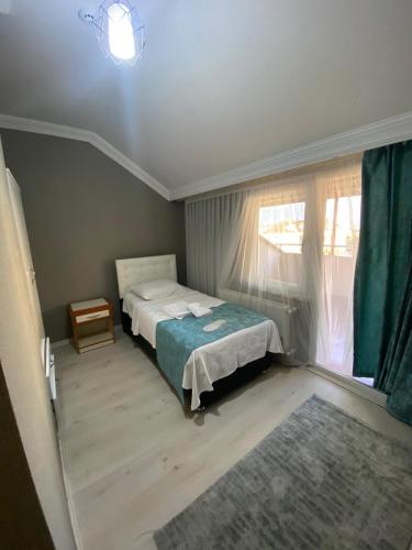 a small bedroom with a bed and a window at TULİPA SUİTEs TRABZON in Bostancı