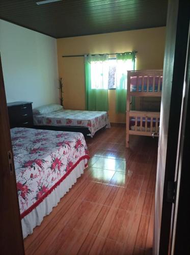a bedroom with two beds and a wooden floor at Chácara com Piscina e Lareira para Alugar em Munhoz MG in Cambuí