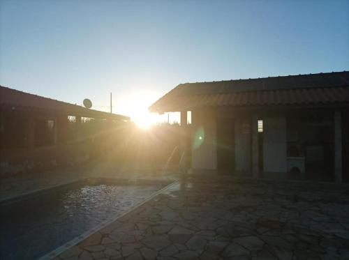 a sun setting behind a building with a swimming pool at Chácara com Piscina e Lareira para Alugar em Munhoz MG in Cambuí