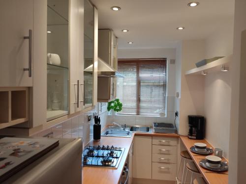a kitchen with white cabinets and a stove top oven at Cosy Apartment in North London - Great Location in London