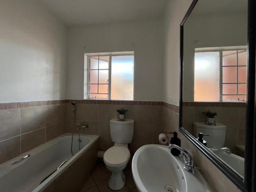 a bathroom with a toilet and a tub and a sink at Siena Sun 09 in Midrand