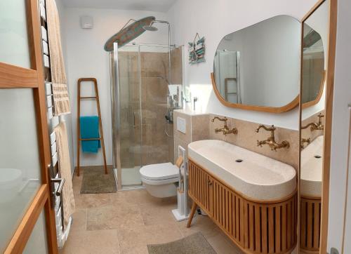 une salle de bain avec un lavabo, des toilettes et un miroir dans l'établissement Villa Soleil, 300m de la plage, au Grau-dʼAgde