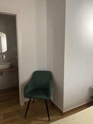 a green chair in a bathroom with a sink at Al Duomo Suites in Monreale
