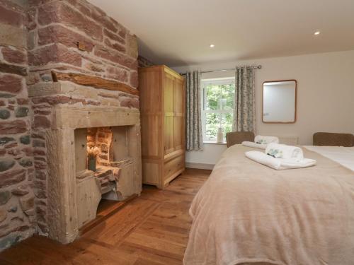 a bedroom with two beds and a stone fireplace at Heather's Cottage in Carlisle