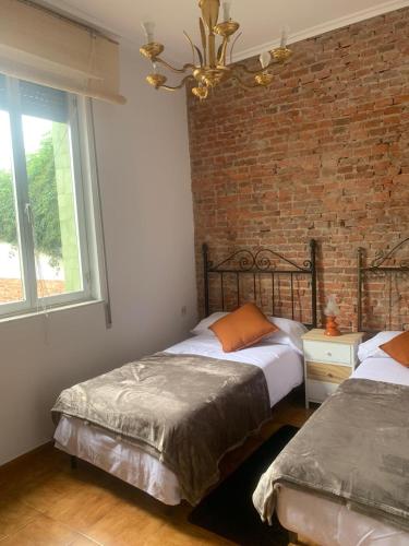 a bedroom with two beds and a brick wall at Villa Caamaño in Gijón
