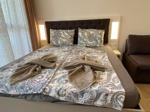 a bed with two towels on it with a couch at КАСКАДАС Луксозни нови студия in Sunny Beach