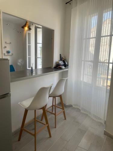 - une cuisine avec 2 chaises blanches et un comptoir dans l'établissement Etoile de Mer Magnifique STUDIO Déco Plage et sable fin, Votre séjour à Marseille commence ici, Centre-Ville, à Marseille