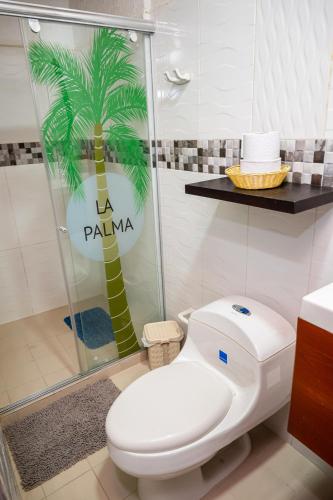 a bathroom with a toilet and a palm tree on the wall at Hotel La Palma Centro Histórico in Santa Marta