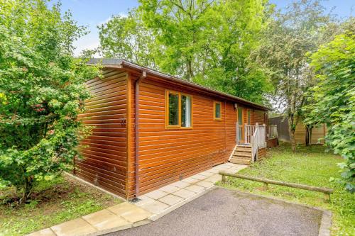 a small wooden cabin with a porch in a yard at Blenheim Lodge 21 in Kingham