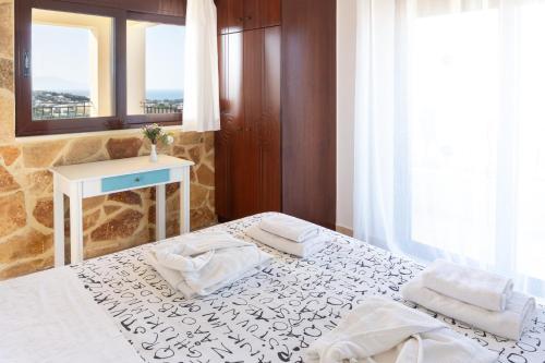 a bedroom with two beds and a table and a mirror at Pasiphae villas 1 & 2 in Stalos
