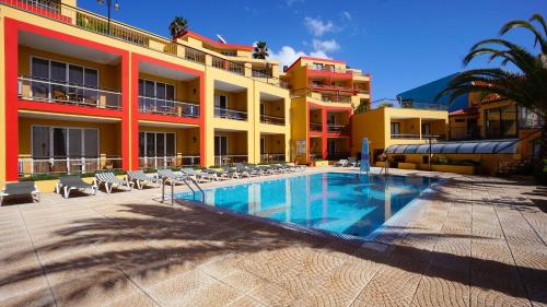 a hotel with a swimming pool in front of a building at Hotel Cais da Oliveira in Caniço