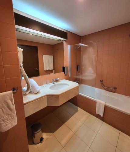 a bathroom with a sink and a shower and a tub at Hotel Cais da Oliveira in Caniço