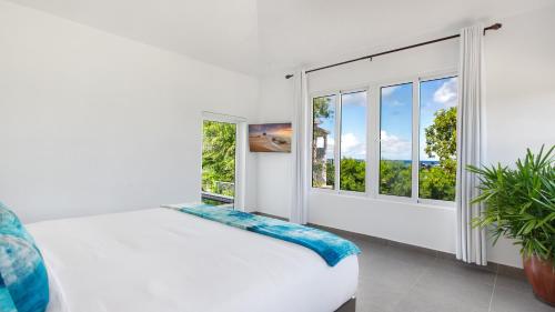 een witte slaapkamer met een bed en een raam bij Châlet Genesis in Meads Bay