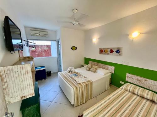 a room with two beds and a flat screen tv at Pousada Baía das Conchas in Ubatuba