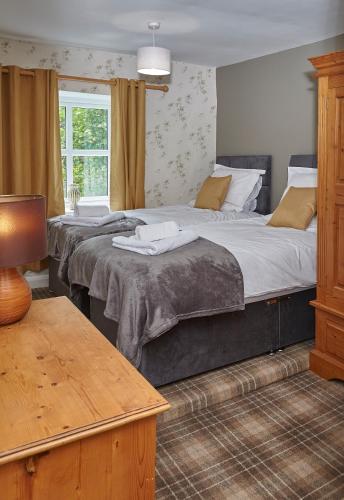 two large beds in a bedroom with a window at Keepers Cottage Serviced Accommodation Yorkshire in Sowerby Bridge