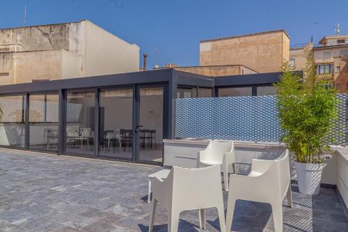 a patio with white chairs and a table on a building at Isgrò Rooms in Marsala