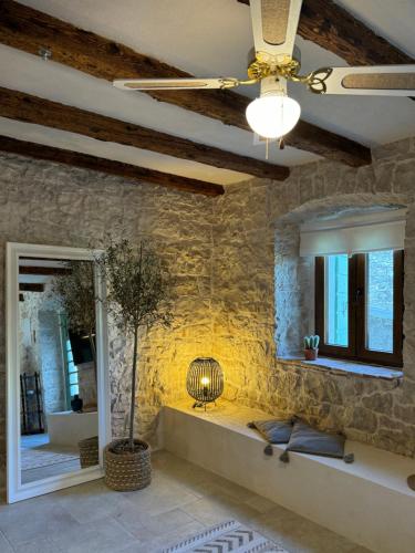 een woonkamer met een plafondventilator en een stenen muur bij NEW 2024! Casa Vecchia in Višnjan