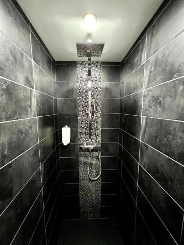 La salle de bains est pourvue d'une douche avec du carrelage noir. dans l'établissement SUNNY , terrasse, climatisation, centre ville, à Carcassonne