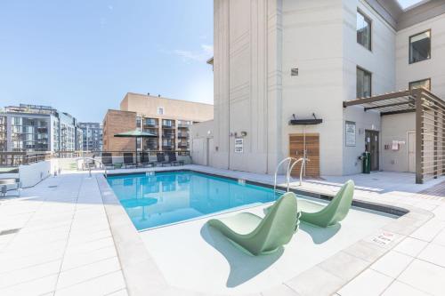 a swimming pool with two green chairs next to a building at Elegant 2BR Apartment Minutes From DC in Arlington