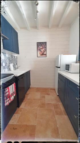 Il comprend une cuisine avec des placards bleus et du carrelage. dans l'établissement Le clos Taquois - gîte 6 pers piscine et jacuzzi, à Villetrun