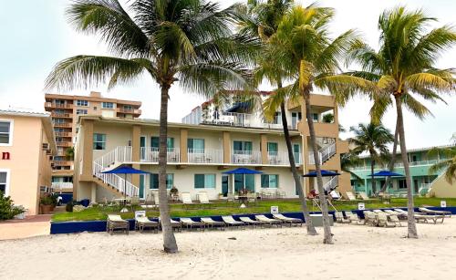 a hotel on the beach with chairs and palm trees at Enchanted Isle Hollywood Beach Resort in Hollywood