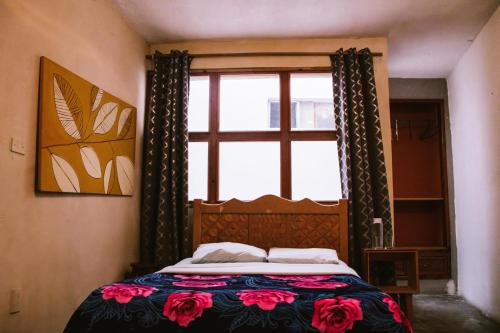 a bedroom with a bed and a window with flowers at Casa Satoshi in San Cristóbal de Las Casas