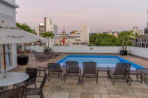 a patio with chairs and a swimming pool on a building at Plaza Blumenau Hotel in Blumenau