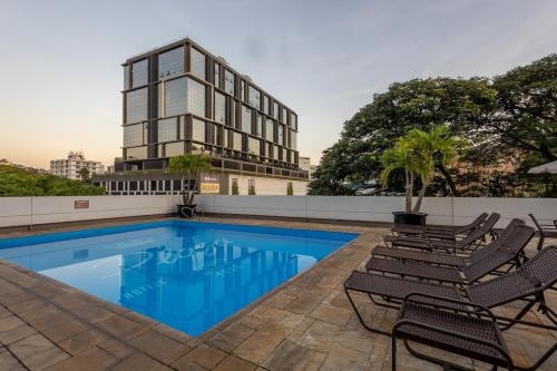 a swimming pool with chairs and a building in the background at Plaza Blumenau Hotel in Blumenau