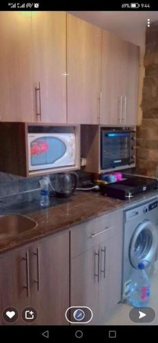 a kitchen with a microwave and a stove and a sink at Chalet with garden portogolf in Al Wiḩdah