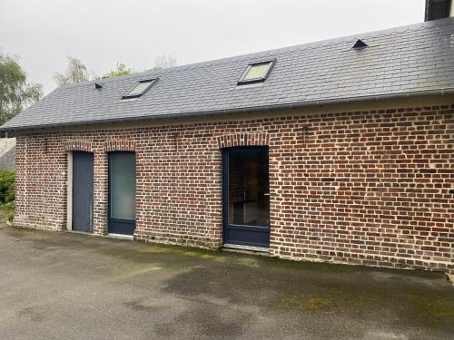 a brick building with two windows and a door at Le Cartot in Saint-Sauveur-dʼÉmalleville